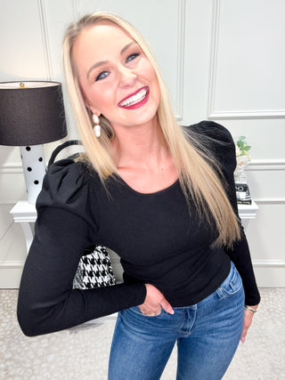 Classic black top with round neckline and puff sleeves.